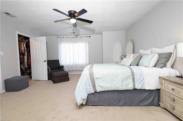 bedroom featuring light carpet, a walk in closet, a closet, and ceiling fan