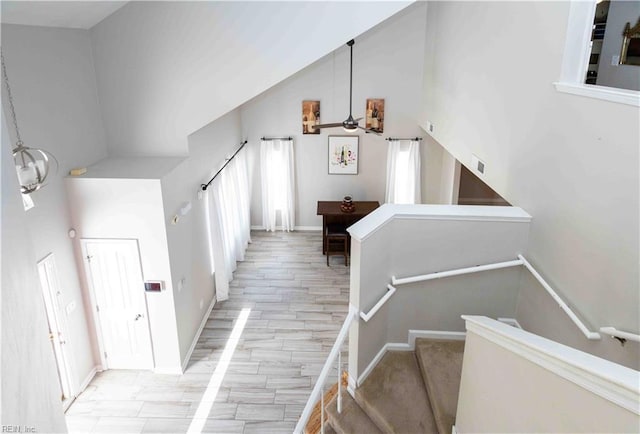 staircase featuring high vaulted ceiling and hardwood / wood-style floors