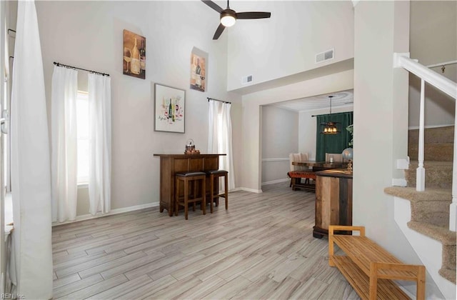 interior space featuring a towering ceiling, ceiling fan with notable chandelier, and light hardwood / wood-style floors