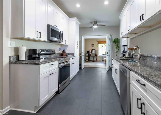 kitchen featuring white cabinetry, stainless steel appliances, sink, and dark stone counters