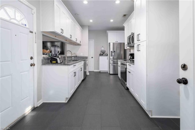 kitchen with dark stone countertops, sink, stainless steel appliances, and white cabinets