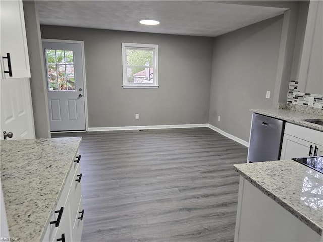 kitchen featuring light stone countertops, white cabinets, decorative backsplash, hardwood / wood-style flooring, and stainless steel dishwasher