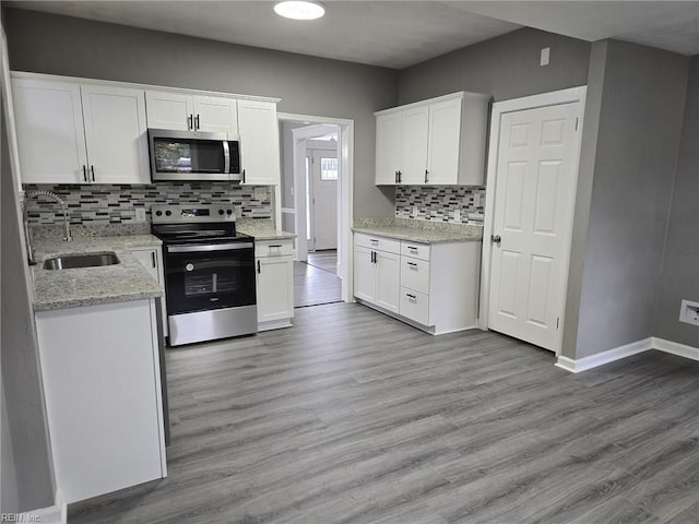 kitchen featuring light hardwood / wood-style floors, appliances with stainless steel finishes, tasteful backsplash, white cabinets, and sink