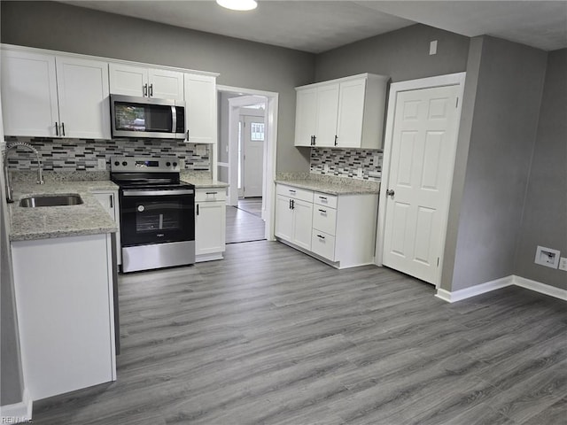 kitchen with white cabinets, stainless steel appliances, light wood-type flooring, and sink