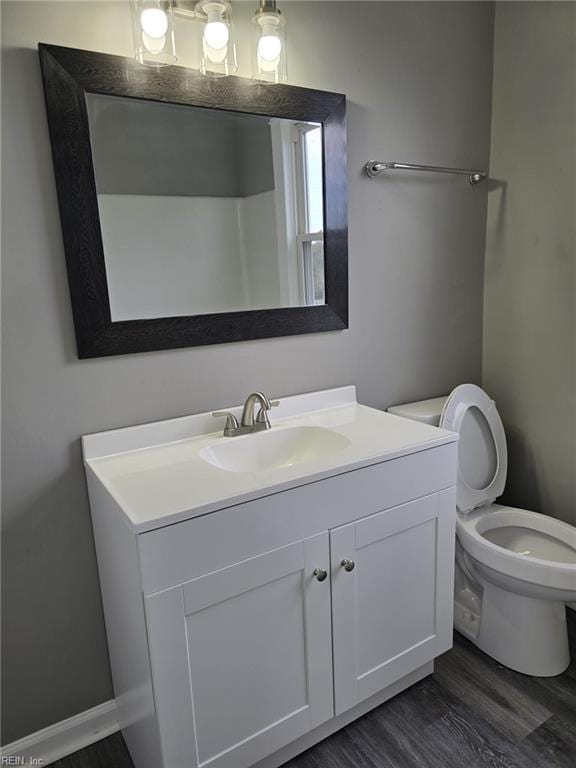 bathroom with hardwood / wood-style flooring, toilet, and vanity