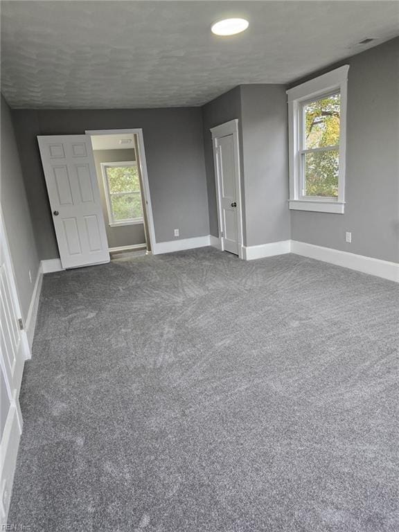 carpeted empty room with a healthy amount of sunlight and a textured ceiling