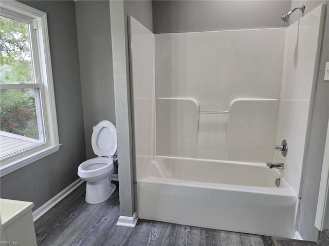 bathroom featuring washtub / shower combination, a healthy amount of sunlight, hardwood / wood-style floors, and toilet