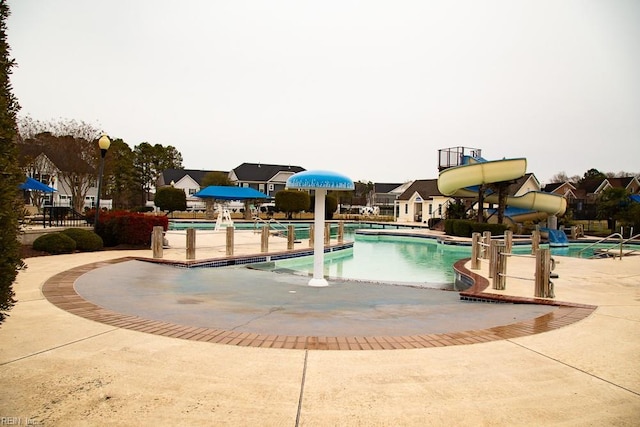 view of pool with a water slide and a patio area