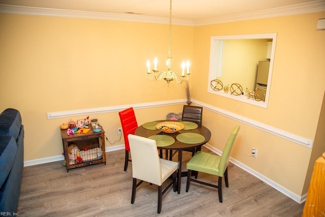 dining space featuring hardwood / wood-style flooring, ornamental molding, and an inviting chandelier