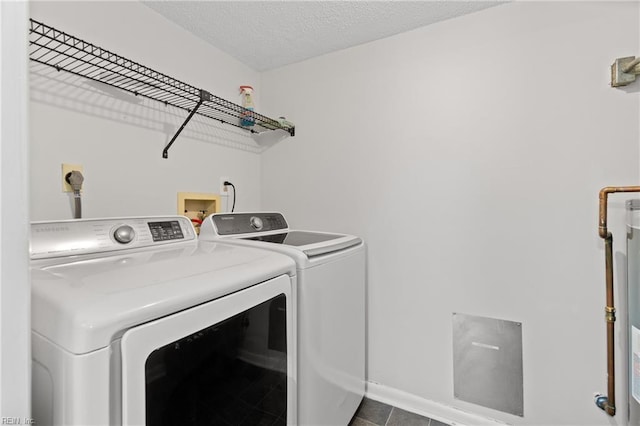 clothes washing area with a textured ceiling, washing machine and dryer, and tile patterned flooring