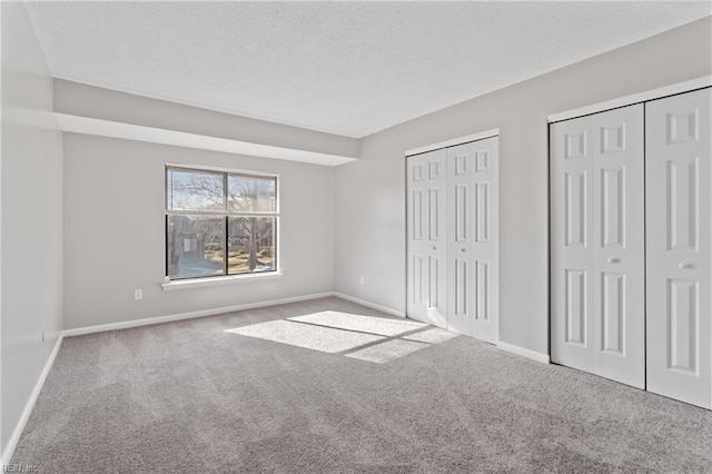 unfurnished bedroom featuring two closets and carpet flooring