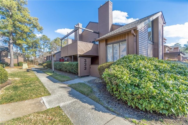 view of property exterior with a balcony and a lawn