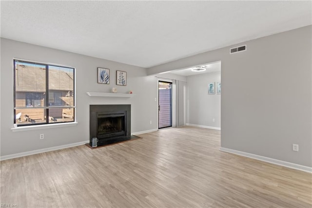 unfurnished living room with plenty of natural light and light hardwood / wood-style flooring