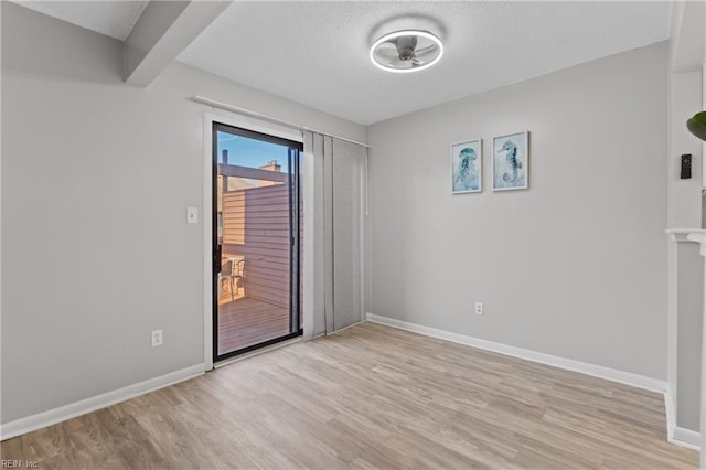 empty room with beam ceiling and light hardwood / wood-style floors