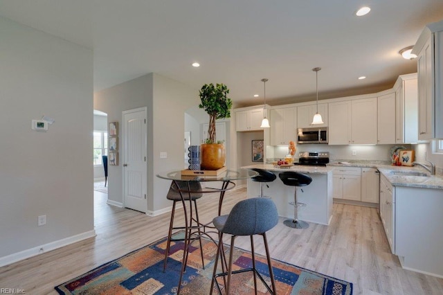 kitchen with pendant lighting, sink, appliances with stainless steel finishes, a center island, and white cabinets