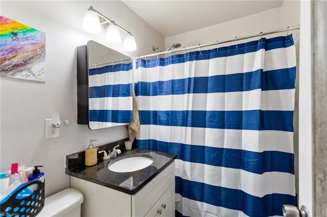 bathroom featuring toilet, walk in shower, and vanity