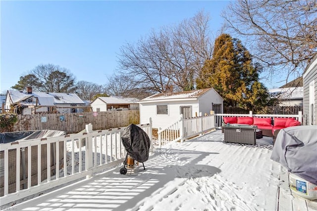 snow covered deck with outdoor lounge area, an outbuilding, a garage, and a grill