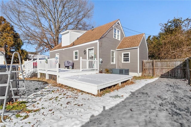 snow covered back of property with cooling unit and a wooden deck