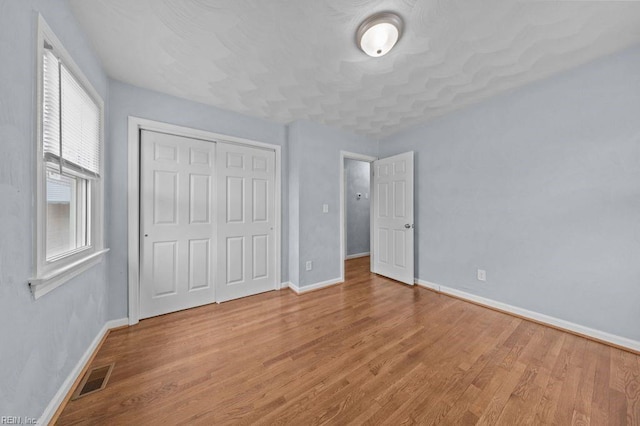 unfurnished bedroom with light wood-type flooring and a closet