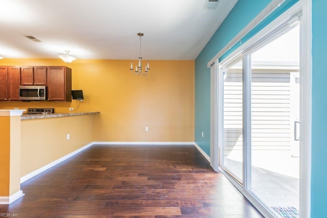 kitchen with pendant lighting, a chandelier, appliances with stainless steel finishes, and dark wood-type flooring