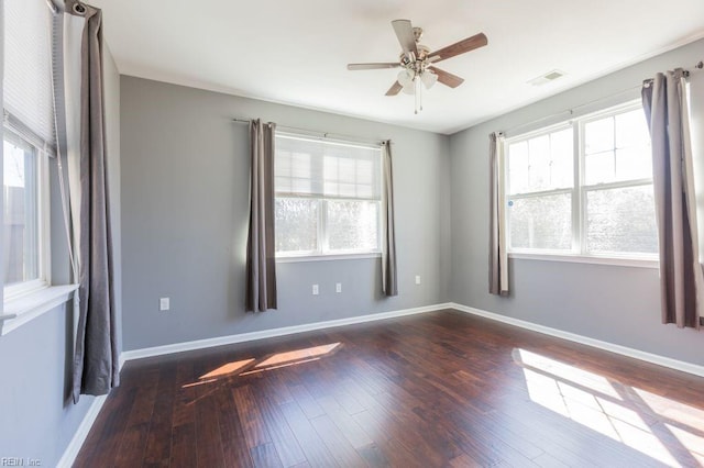 empty room featuring plenty of natural light, ceiling fan, and dark hardwood / wood-style flooring