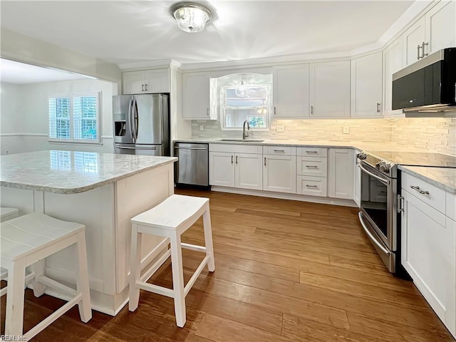 kitchen featuring sink, white cabinets, a breakfast bar area, and appliances with stainless steel finishes