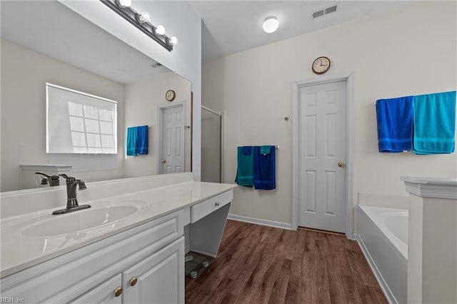 bathroom with hardwood / wood-style floors, a tub to relax in, and vanity