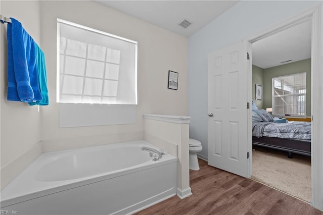 bathroom with hardwood / wood-style flooring, toilet, and a bath