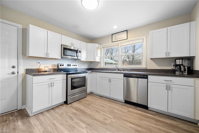 kitchen featuring white cabinets, appliances with stainless steel finishes, light hardwood / wood-style flooring, and sink