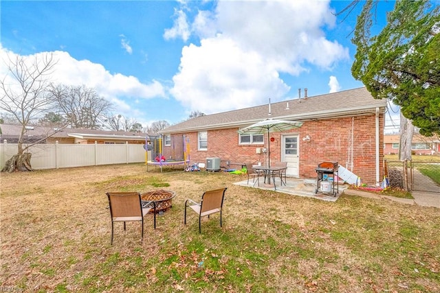 back of house featuring a fire pit, central AC, a lawn, and a trampoline