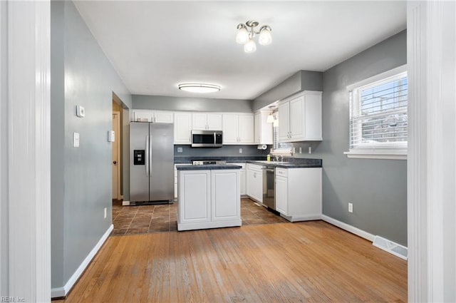 kitchen with sink, light hardwood / wood-style flooring, appliances with stainless steel finishes, white cabinets, and a kitchen island