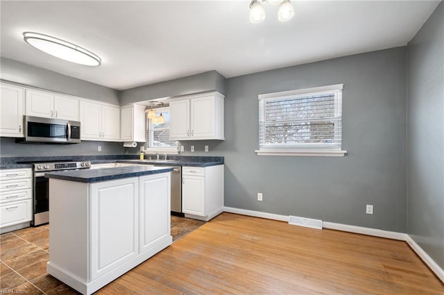 kitchen featuring stainless steel appliances, a center island, and white cabinets