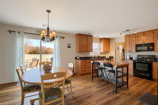 kitchen featuring decorative light fixtures, a notable chandelier, hardwood / wood-style flooring, and black appliances