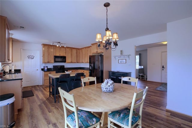 dining space with sink, an inviting chandelier, track lighting, and dark hardwood / wood-style flooring