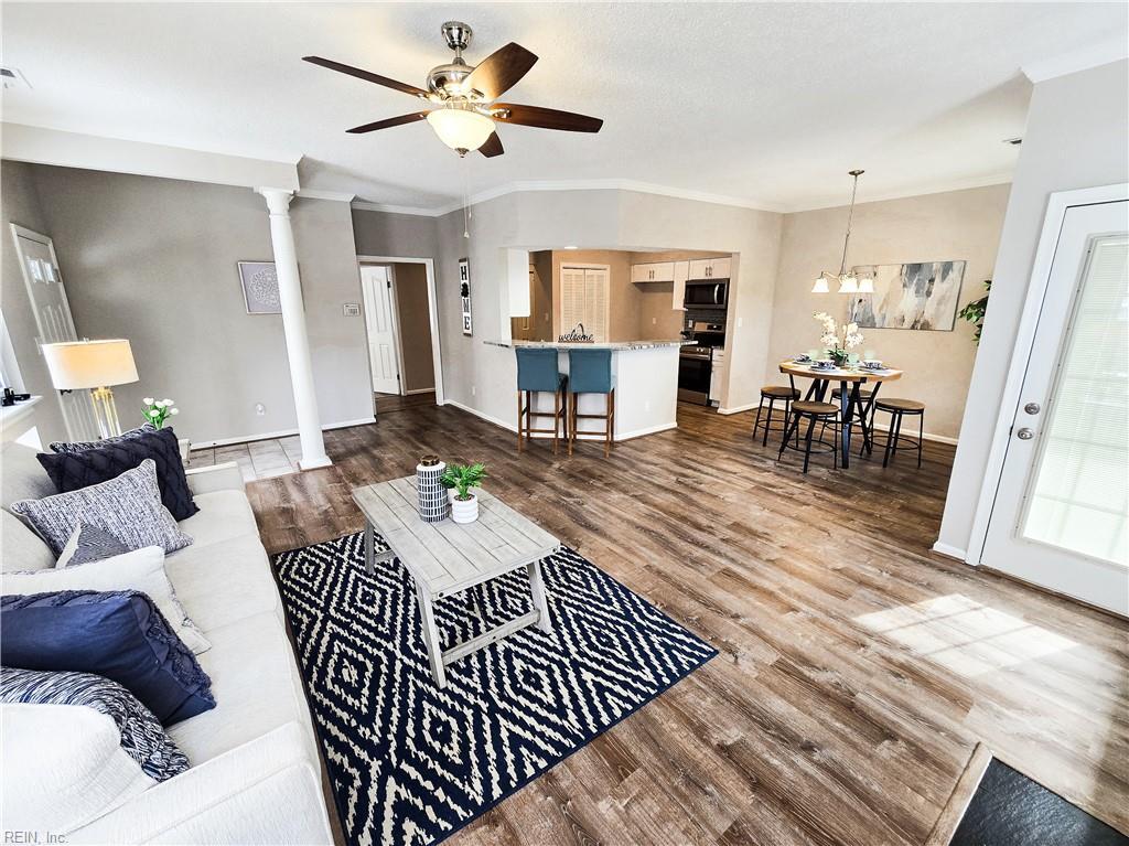 living room with hardwood / wood-style floors, ornamental molding, ceiling fan, and ornate columns