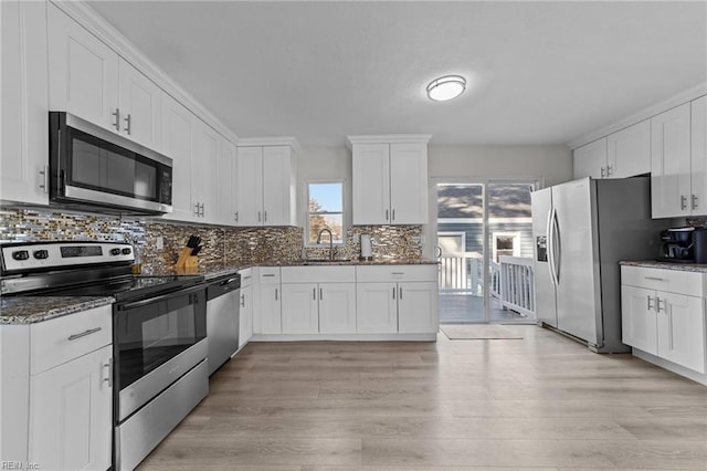 kitchen with white cabinetry, sink, decorative backsplash, light hardwood / wood-style floors, and stainless steel appliances