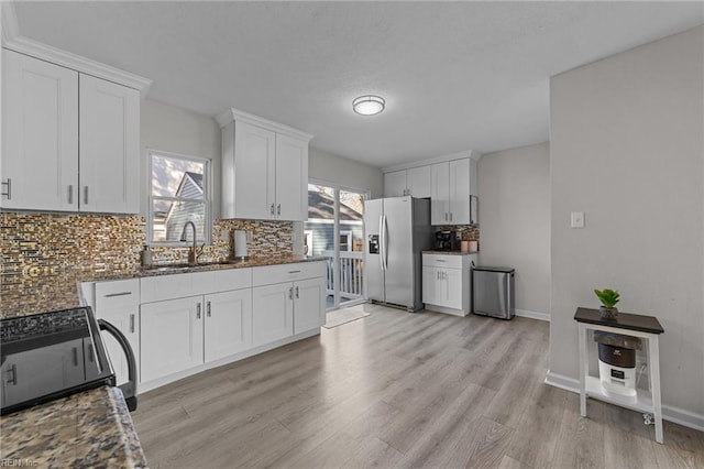 kitchen with tasteful backsplash, sink, white cabinets, stove, and stainless steel fridge with ice dispenser