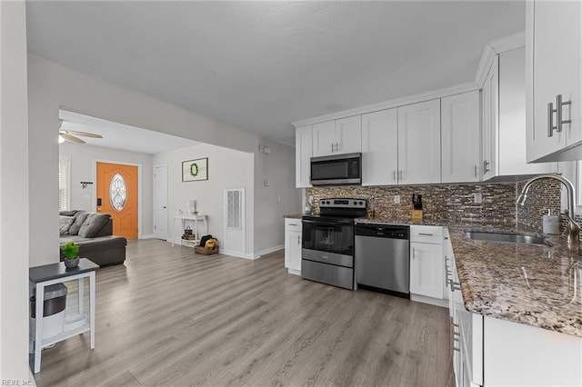 kitchen featuring sink, stone countertops, stainless steel appliances, decorative backsplash, and white cabinets