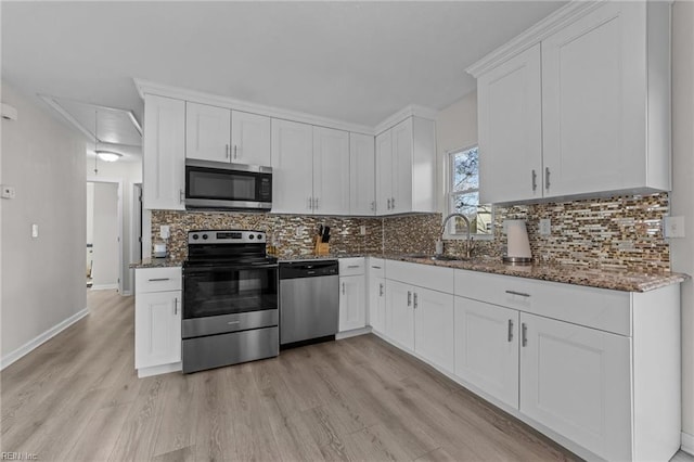 kitchen with white cabinetry, appliances with stainless steel finishes, sink, and dark stone counters