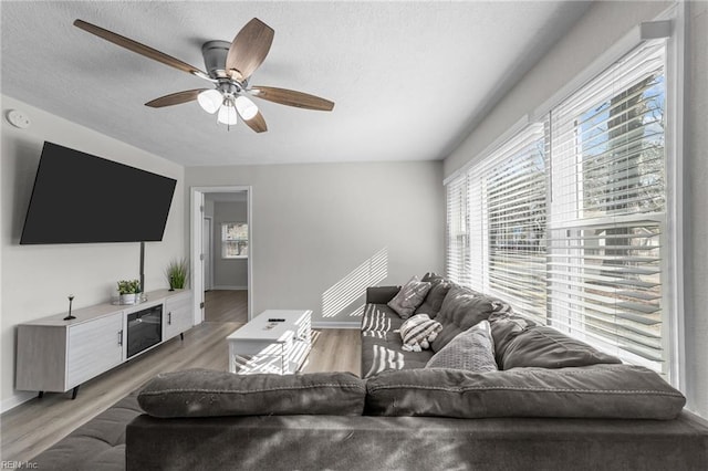 living room with ceiling fan, light hardwood / wood-style floors, and a textured ceiling