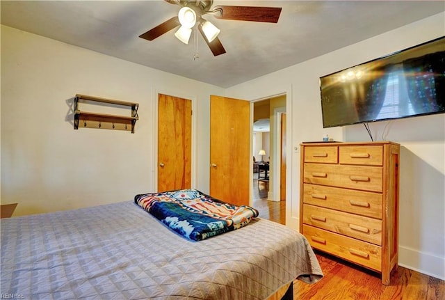 bedroom featuring multiple closets, light hardwood / wood-style flooring, and ceiling fan