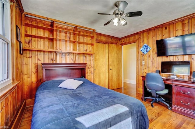 bedroom featuring hardwood / wood-style floors, ceiling fan, and wood walls