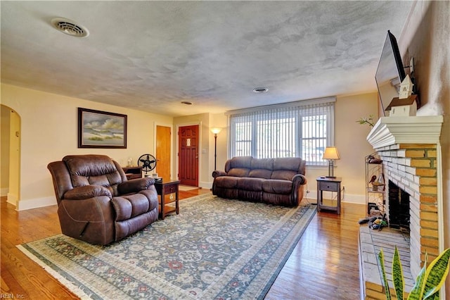 living room with wood-type flooring and a brick fireplace