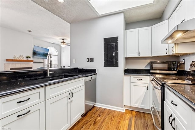 kitchen with light hardwood / wood-style floors, white cabinetry, sink, dark stone countertops, and stainless steel appliances