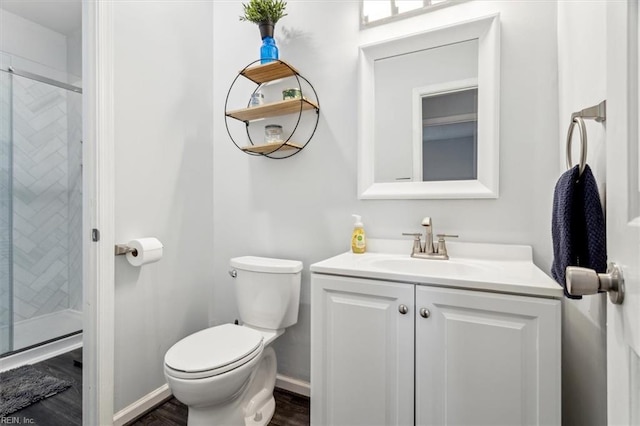 bathroom featuring a shower with door, toilet, and vanity