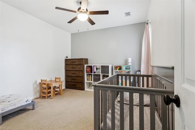 bedroom featuring ceiling fan, carpet flooring, and a crib