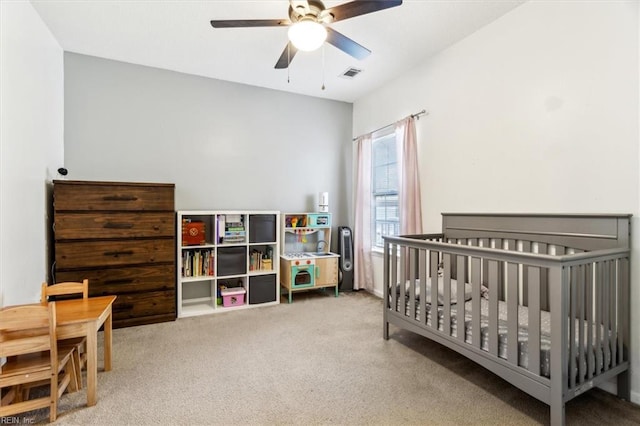 bedroom with ceiling fan, a nursery area, and light colored carpet