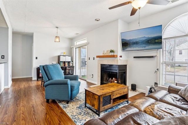 living room featuring a tiled fireplace, hardwood / wood-style flooring, and ceiling fan