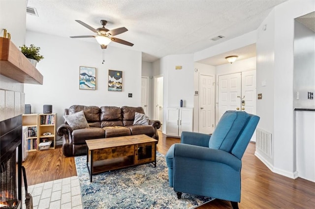 living room featuring a textured ceiling, ceiling fan, and dark hardwood / wood-style flooring