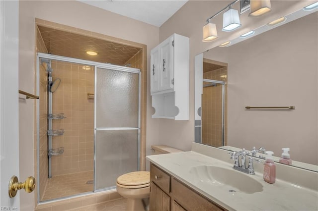 bathroom featuring toilet, vanity, and a shower with shower door